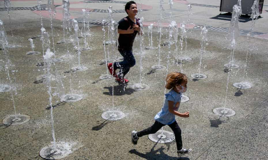 Kids run through water spouts as they cool off in Los Angeles, California, as the state sees extreme temperatures.
