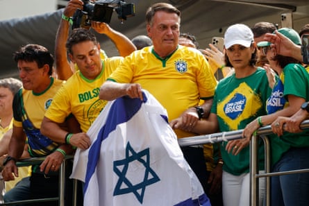 Jair Bolsonaro waves an Israeli flag as he greets supporters.