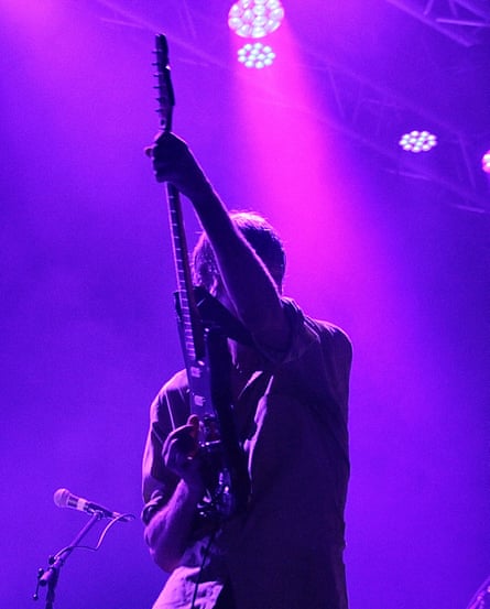Pavement jouant au Anita's Theatre à Thirroul, NSW en Australie le 1er mars 2023. La scène est baignée de lumière violette et de brume tandis qu'un homme jouant de la guitare la tient debout devant son torse