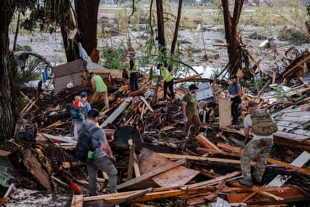 Search and rescue workers amid heaps of wood, planks and panels of a destroyed building at the riverside