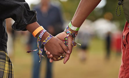 Young couple with wristbands holding hands at music festival