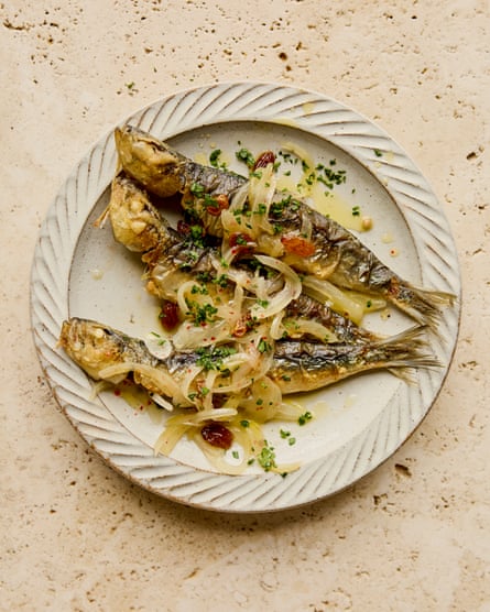 A plate of three sardines with oil, parsely and onions.