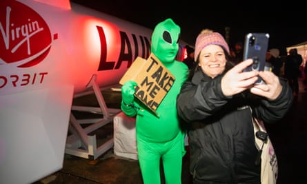 A woman takes a selfie with Adrian Grint, dressed as an alien at the inaugural rocket launch