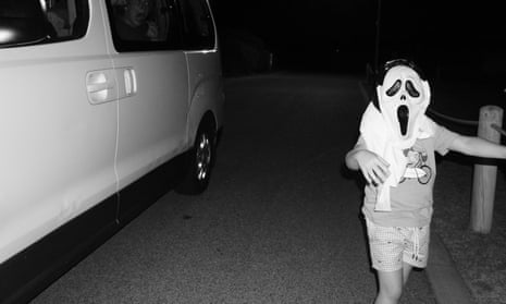 A child dressed up as a ghost with a white van in the background