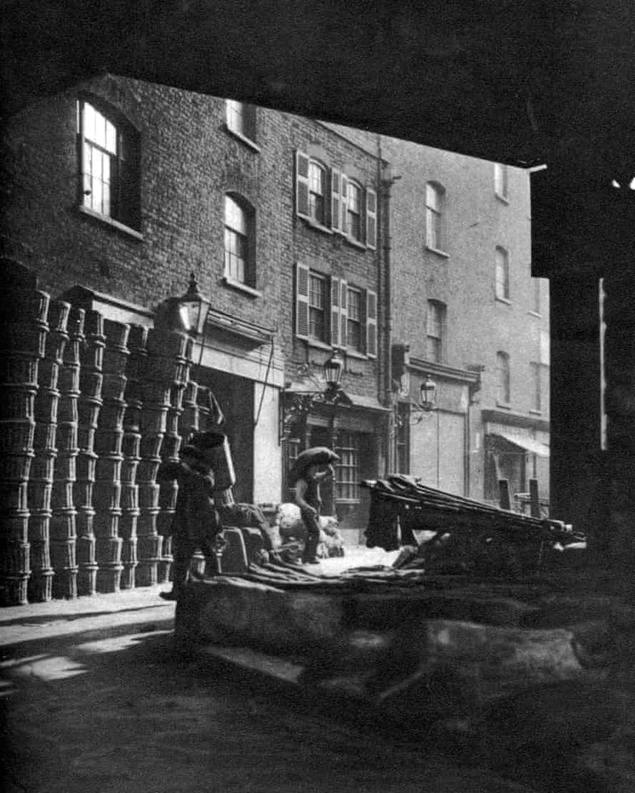 Fruit baskets piled against houses at borough market in the 1920s
