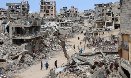 Palestinians walk on a road lined with destroyed building in the Shujaiya neighbourhood of Gaza City