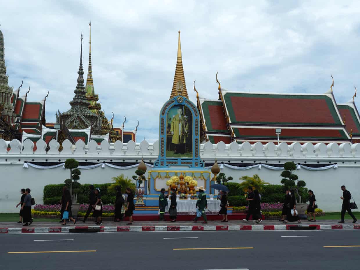 People walk along a pavement outside the Grand Palace