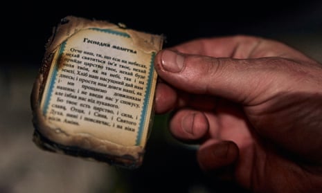 A Ukrainian soldier holds a partially burnt prayer book.