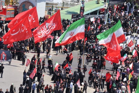 People wave flags on the street for the funeral procession.