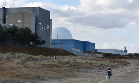 A woman walks her dogs along the beach next to the Sizewell B nuclear power station