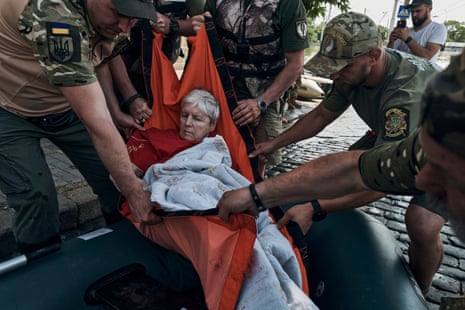 Los trabajadores de emergencia evacuan a un residente anciano en un bote de goma de un vecindario inundado en Kherson.