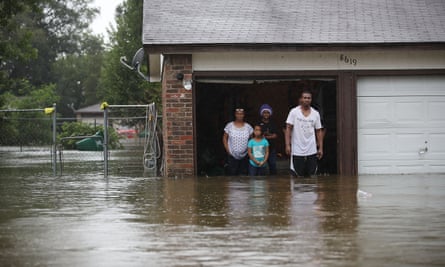 People stand with water up to their knees in a flooded house in Houston, Texas.