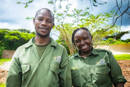 A smiling man and a woman wearing rangers green shirts standing outside.