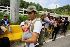 A man carries a baby as he walks with other Hondurans fleeing poverty and violence as they move in a caravan toward the United States, in the west side of Honduras.