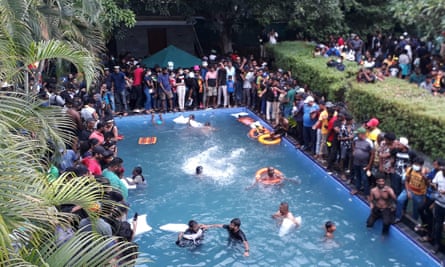A dozen people in a pool surrounded by people watching from the sides