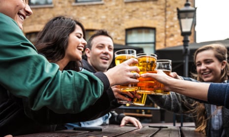 Young people toast with beers outside a pub in London