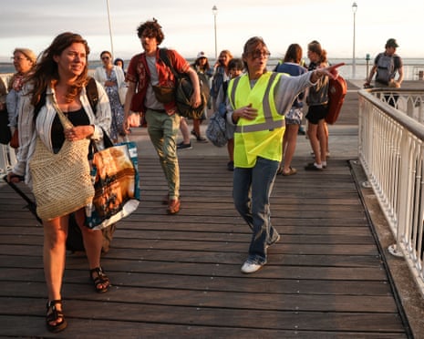 A volunteer gives indication to holidaymakers from Lege-Cap-Ferret upon their arrival in Arcachon by boat during an evacuation operation of the entire Cap-Ferret peninsula, in southwestern France.