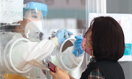 Un operatore medico preleva un campione in una stazione di test Covid-19 improvvisata a Seoul