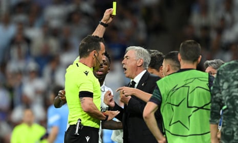 Referee Artur Dias Soares shows a yellow card to Carlo Ancelotti, Head Coach of Real Madrid, after Kevin De Bruyne of Manchester City (not pictured) scored his team's equaliser.