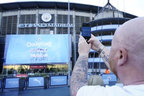 A Manchester City fan takes a photo of the unfurled banner as he celebrates the club’s title victory outside the Etihad.