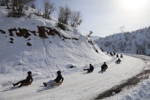 Children sledge down a snowy hill in Elmalı, Turkey
