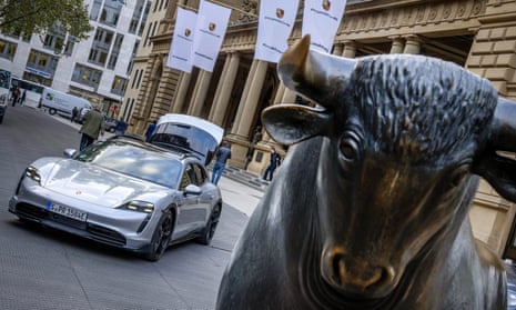 An electric Porsche Taycan is parked behind the bull statue in front of the stock exchange in Frankfurt, Germany.