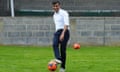 Rishi Sunak kicking an orange football on grass pitch