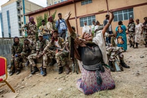 Exhausted Tigrayan soldiers in Mekelle watch a local woman on her knees with outstretched arms appearing to pray