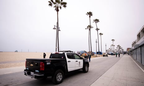 police pickup truck drives along beach near tents