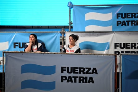 People look on near signs of the Peronist coalition Fuerza Patria