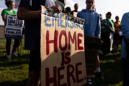 person holds a sign saying ‘emerson’s home is here’ at protest outside