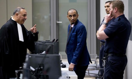 Al Hassan listens as his duty counsel, Yasser Hassan, talks to security guards.