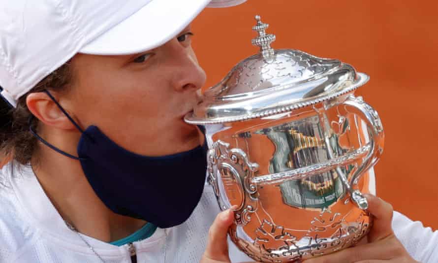 Iga Swiatek kisses her French Open trophy.