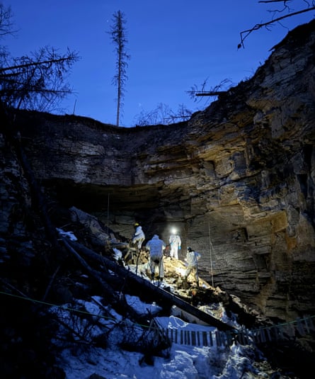 Scientists with headlamps look for bats in caves amid a snowy landscape