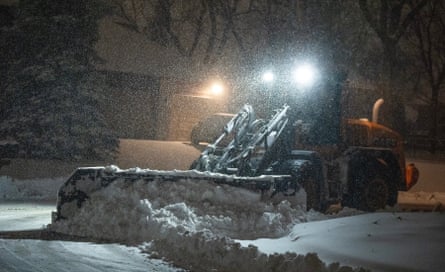 plow pushes snow in dark street