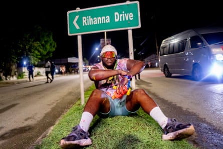 A festival goer revels in activities and poses sat down in front of a ‘Rihanna Drive’ sign in Barbados.