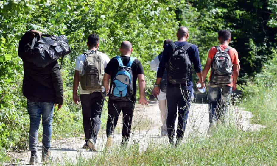 A group of migrants walk through countryside in northern Bosnia after being physically expelled by police from Croatia.