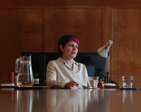 Zoë Garbett sits at a polished desk in an office with wood-paneled walls
