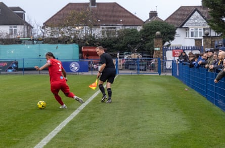 A player on the ball by the touchline and an assistant referee, with about three metres from the touchline to the fencing