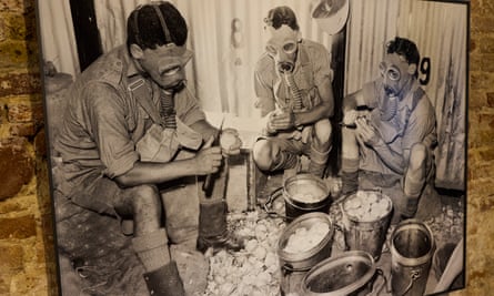 Close up of an artwork of a reproduction of a photograph from 1940 showing Australian soldiers in Gaza wearing gas masks while peeling onions.