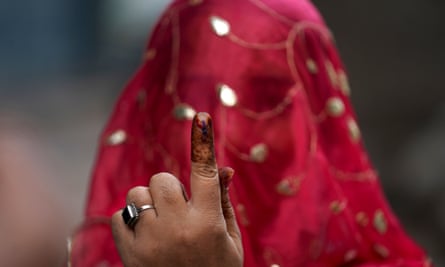 A woman shows the indelible ink mark on her index fingers after casting her vote