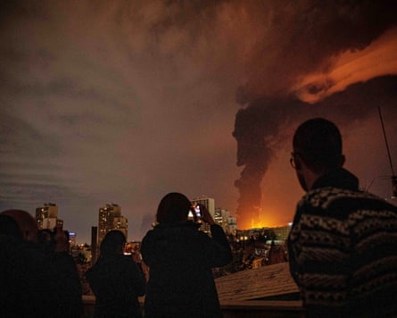 Flames and smoke rise into a dark sky