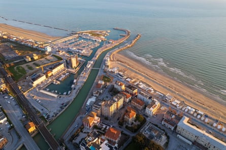 An aerial view of a river running through a town to the sea, cutting through a sandy beach