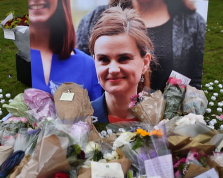 A picture of Cox surrounded by bunches of flowers.