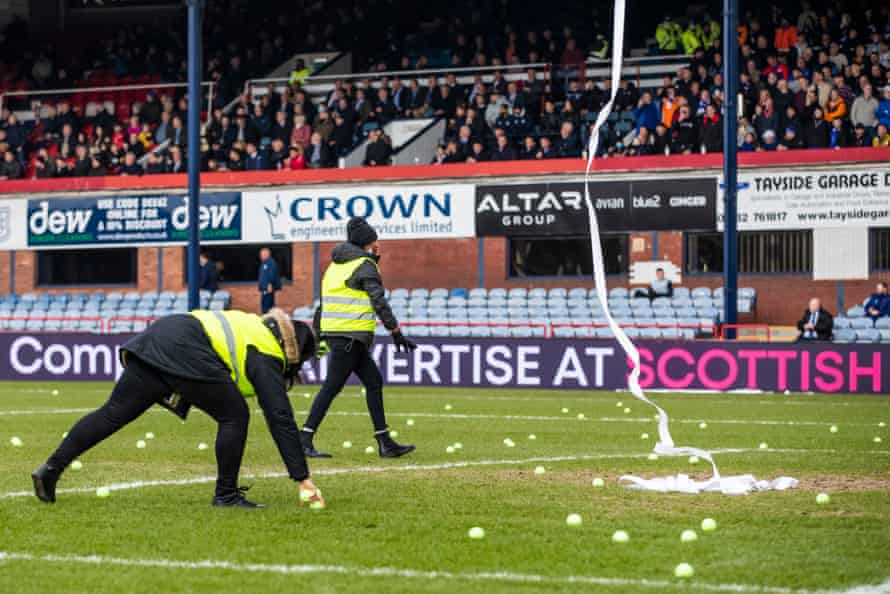 Stewards clear toilet paper and tennis balls from the Dens Park pitch.
