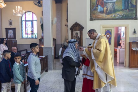 A priest giving holy communion in a mass inside a church