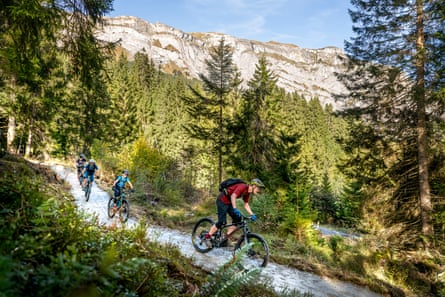 Cyclists going downhill on a wooded mountain bike trail in the mountains