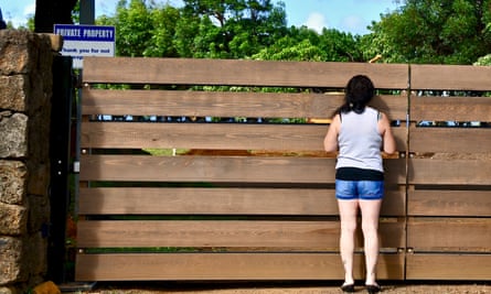 Shannon Buckner peers through the gate surrounding Mark Zuckerberg’s Kauai estate.