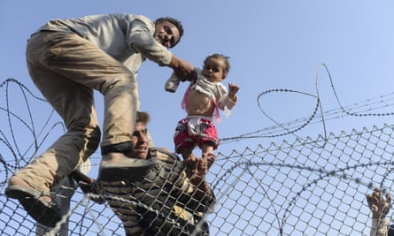 A Syrian child is lifted over border fences near the Turkish border crossing at Akcakale in Sanliurfa province.