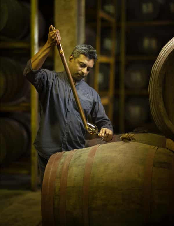 D’Souza is seen pulling whisky from a cask, using a long tube